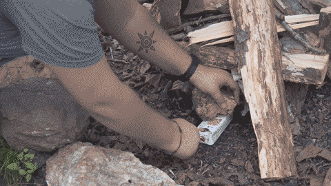 A matchless fire starter igniting wooden logs.